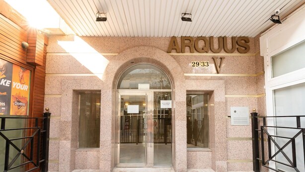 Ingången till en byggnad med en skylt som visar texten ”ARQUUS 2933 V”.