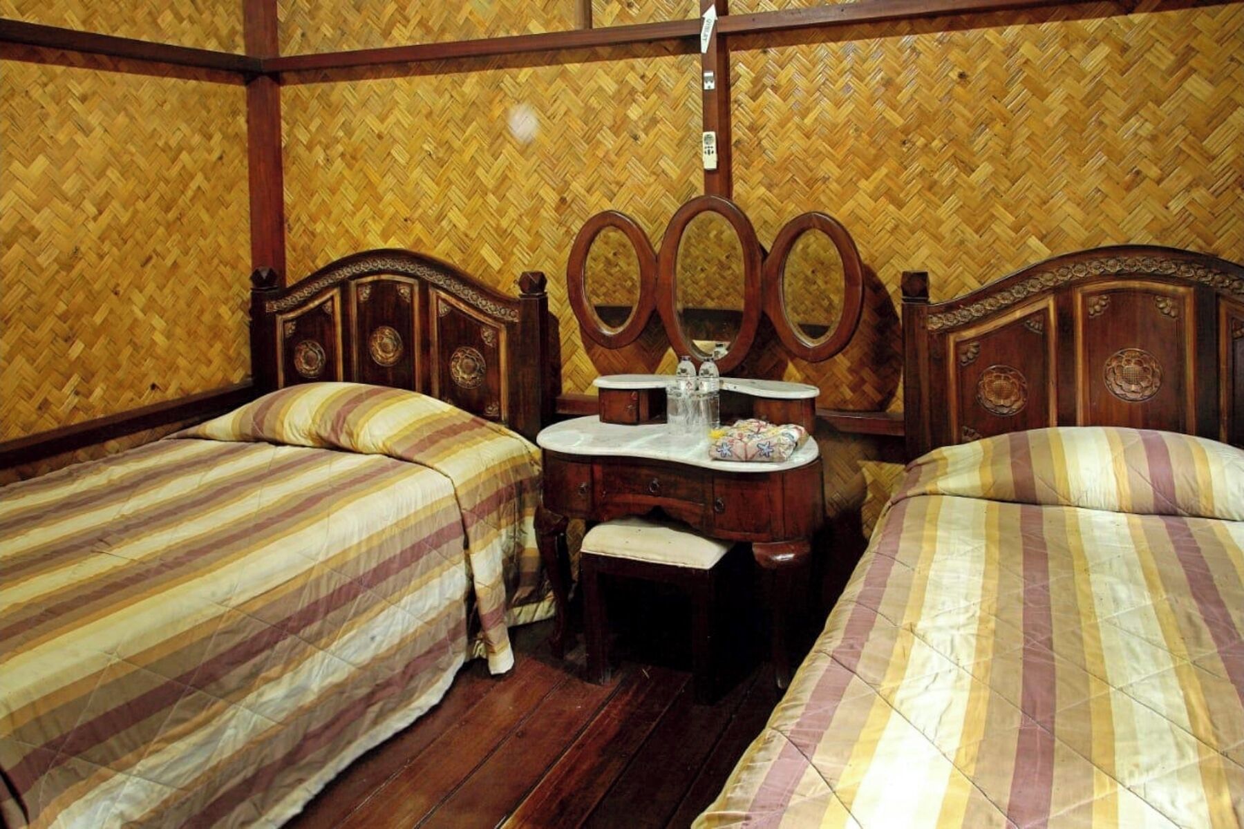 Una habitación con dos camas, un aparador de madera y un espejo.
