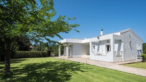 A modern two-story house with a stone facade, a well-maintained lawn, and a large tree providing shade. - Villa Nefeli with Private Pool by Konnect (Corfu)