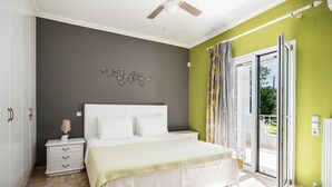 A bedroom with a bed, nightstand, and a view through a sliding glass door. - Villa Nefeli with Private Pool by Konnect (Corfu)