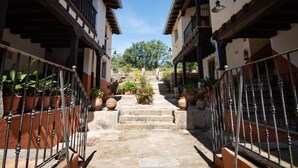 A narrow stone pathway flanked by buildings with balconies and potted plants. - Hospedium Hotel Rural Abadia de Yuste (Cuacos de Yuste)