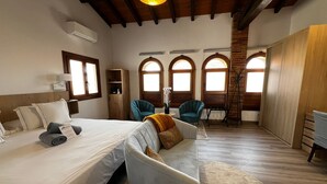 A hotel room with a large bed, two armchairs, a sofa, and a wooden ceiling. - Hospedium Hotel Rural Abadia de Yuste (Cuacos de Yuste)