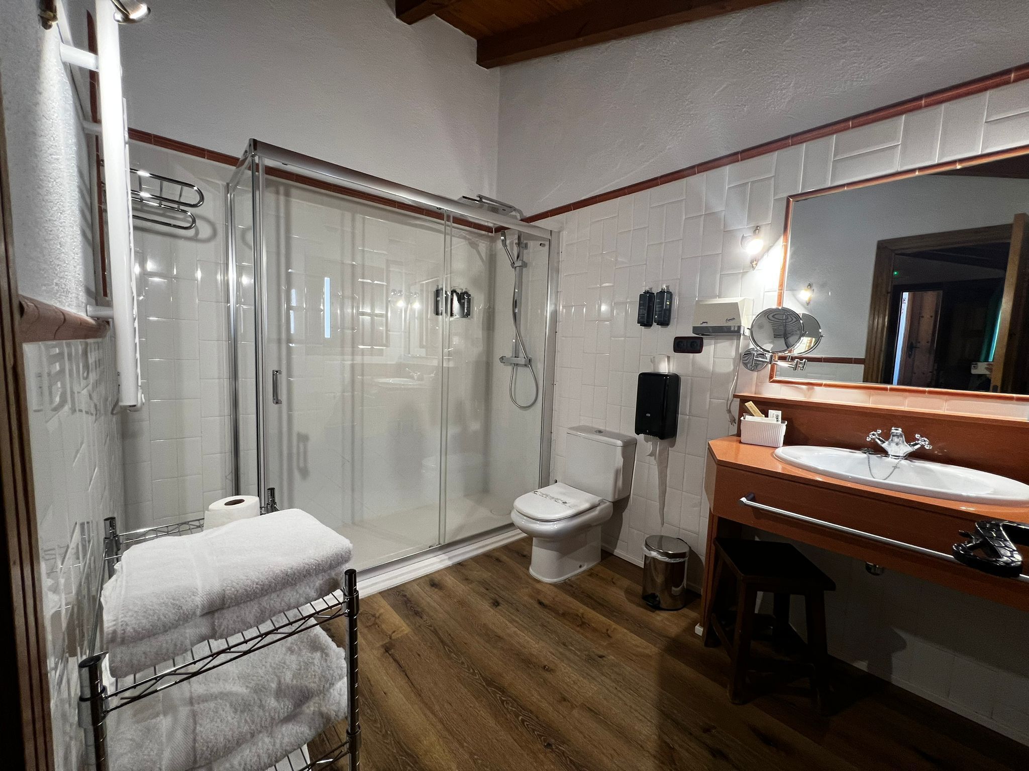 Ein Badezimmer mit Duschkabine, Toilette, Waschbecken mit Spiegel und Handtuchhalter.