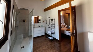 A modern bathroom with a glass shower enclosure, a white vanity, and a wooden ceiling.