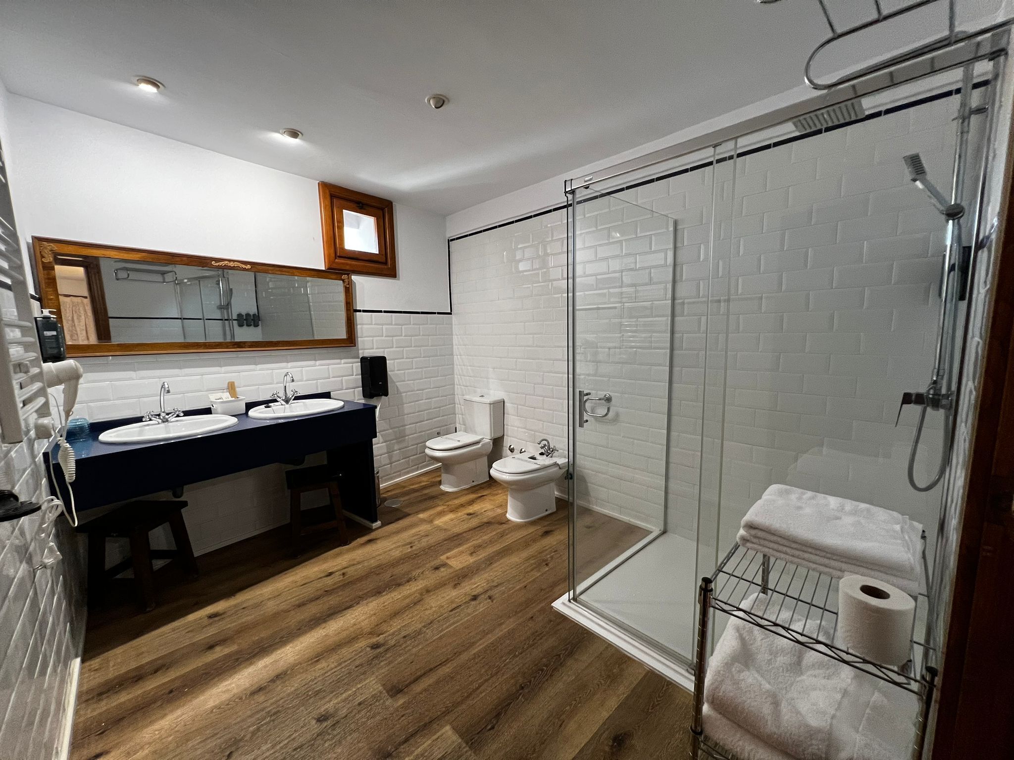 Un baño moderno con tocador doble lavamanos, cabina de ducha con vidrio y un inodoro.