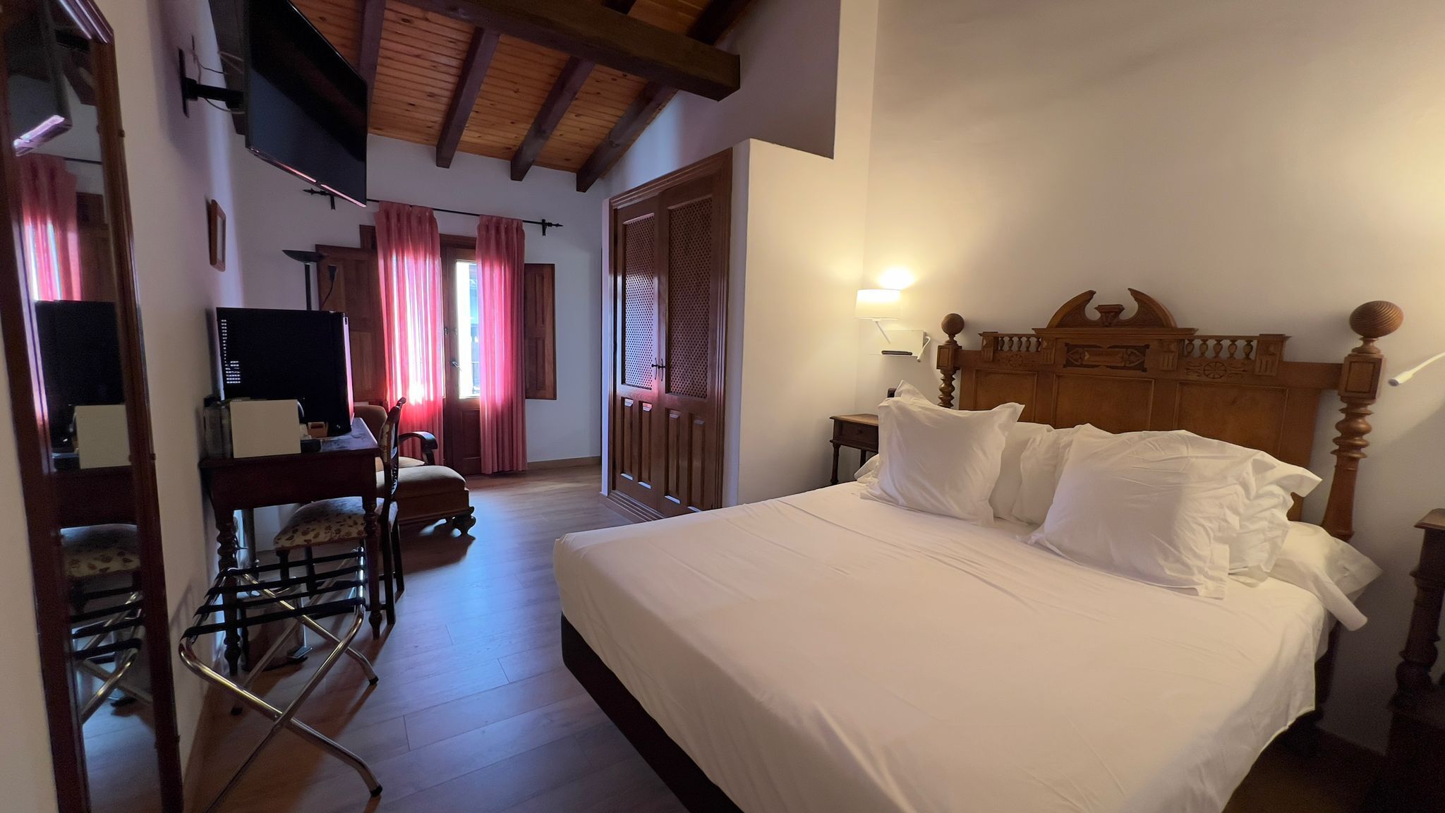 A bedroom with a wooden bed, a desk with a computer, and a chair.