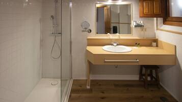 A modern bathroom with a glass-enclosed shower, a sink with a mirror, and wooden cabinets.