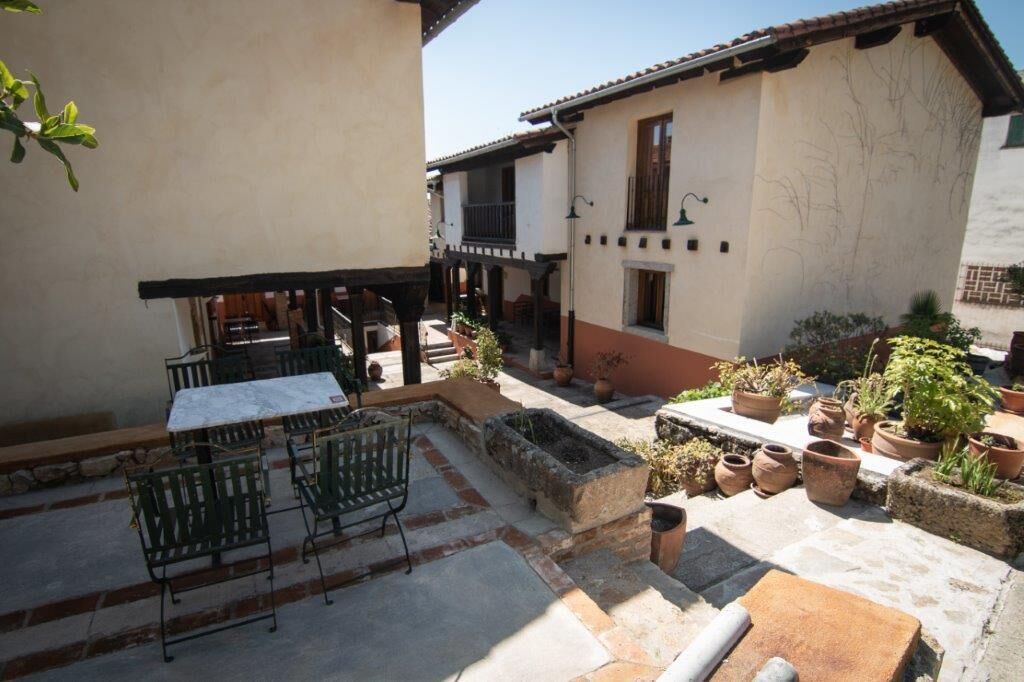 Une cour avec une table et des chaises, des plantes en pot et un bâtiment doté de balcons.