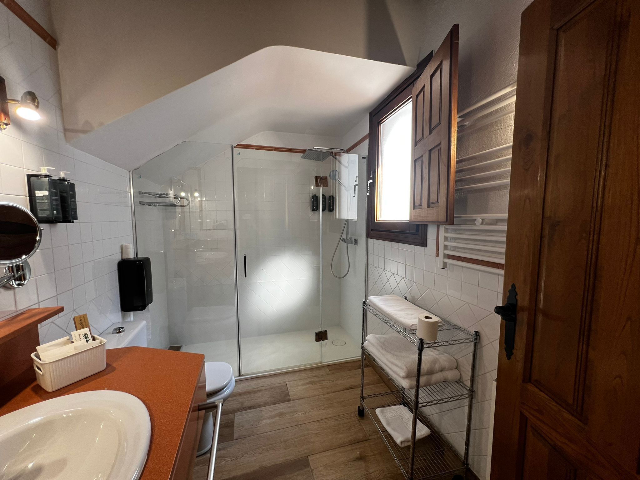 Un baño moderno con cabina de ducha de vidrio, tocador de madera y barra para toallas.
