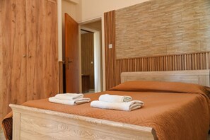 Een slaapkamer met een houten garderobe, een bed met een bruine deken en een hoofdbord met een structuurrijk ontwerp.