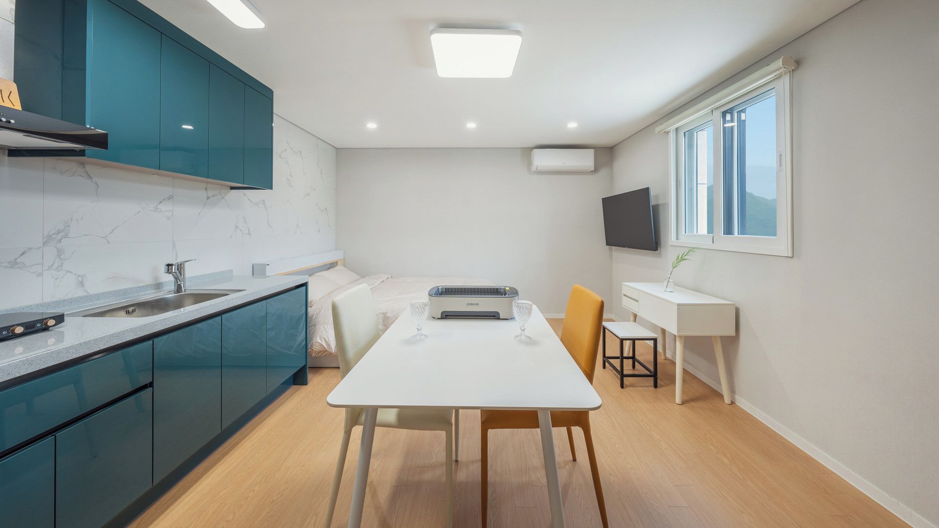 A compact kitchen with teal cabinets, a white countertop, and a built-in stove.