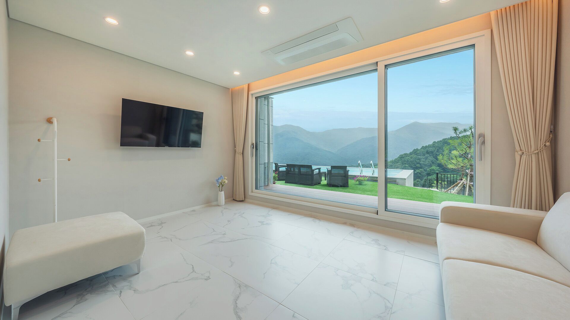 A spacious room with a large sliding glass door leading to a balcony with a mountain view.