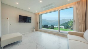 A spacious room with a large sliding glass door leading to a balcony with a mountain view. - Gapyeong Staysumok Pool Villa Pension (Gapyeong)