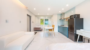 A modern, well-lit kitchen with a refrigerator, stove, and sink. There is a dining area with a white table and chairs. - Gapyeong Staysumok Pool Villa Pension (Gapyeong)