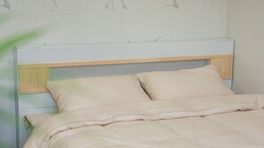 A bed with a wooden headboard and two pillows, set against a wall with a marble-like pattern. - Gapyeong Staysumok Pool Villa Pension (Gapyeong)