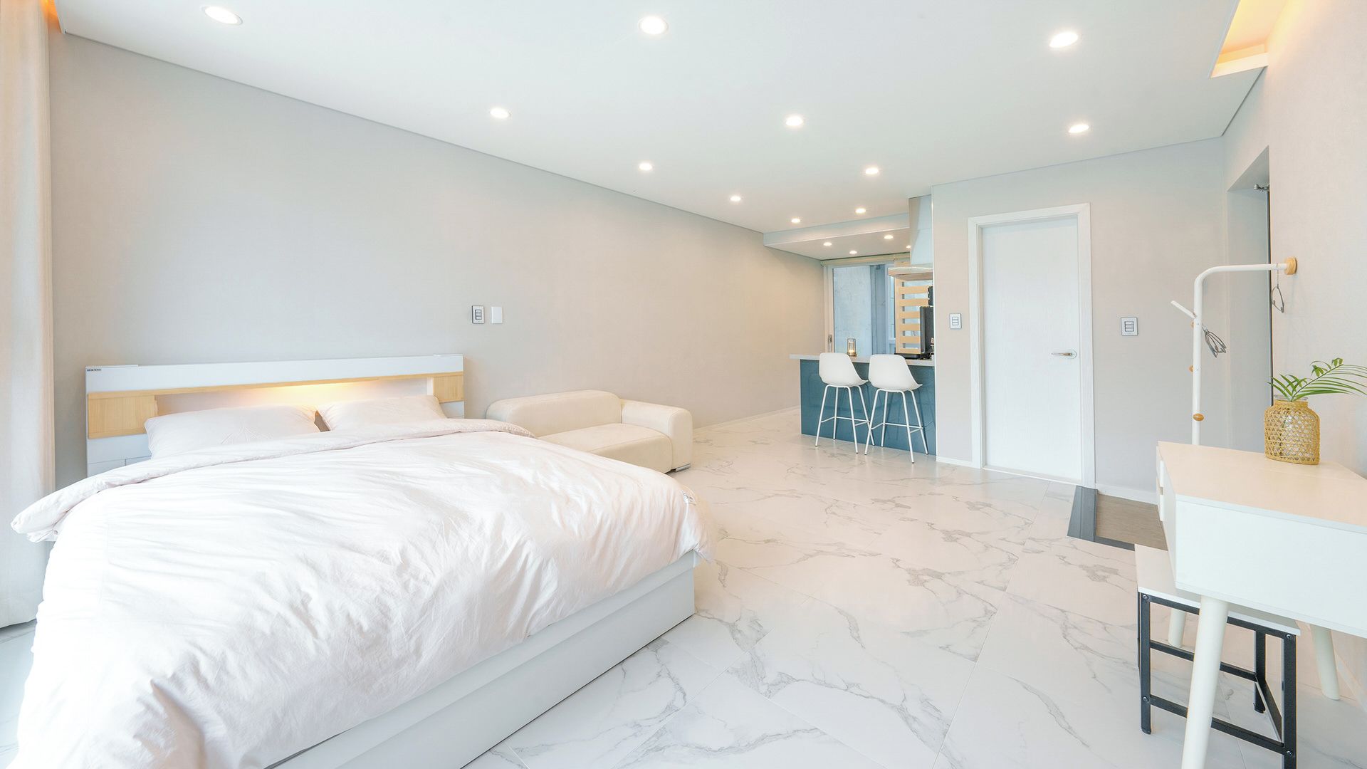 A modern bedroom with a large bed, a desk, and a chair.