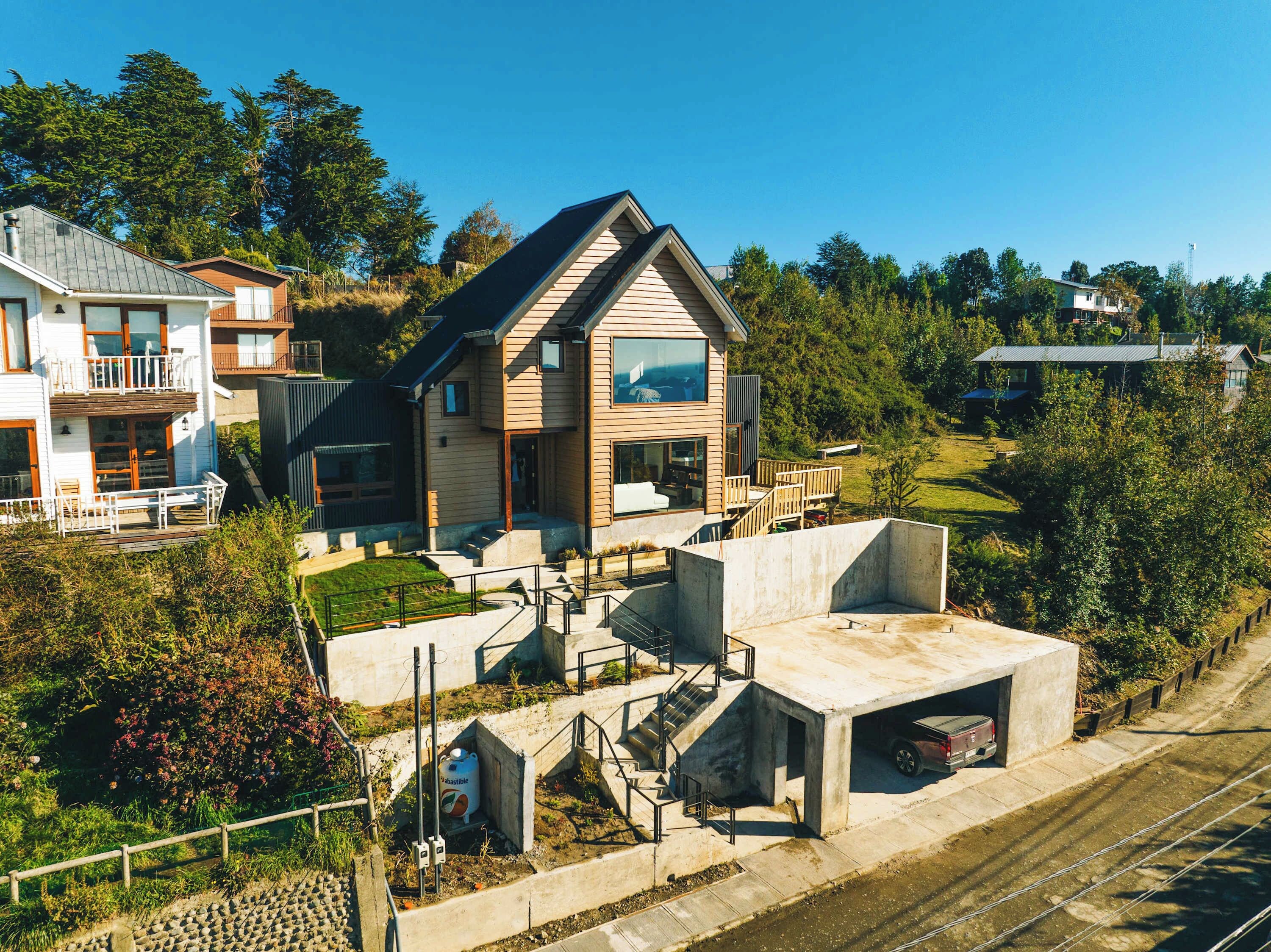A modern two-story house with a large balcony, a garage, and a well-maintained garden.