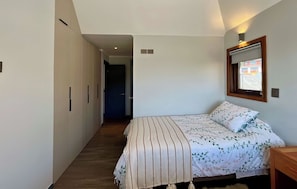 A bedroom with a bed, a nightstand, a wardrobe, and a window.