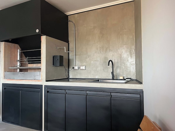 A modern kitchen with a built-in oven, a stainless steel sink, and black cabinetry.