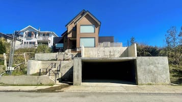 A modern house with a large garage entrance, a balcony, and a clear blue sky.