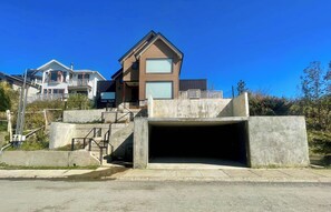 A modern house with a large garage entrance, a balcony, and a clear blue sky.