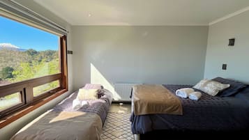 A bedroom with two beds, a view of a mountain, and a window.