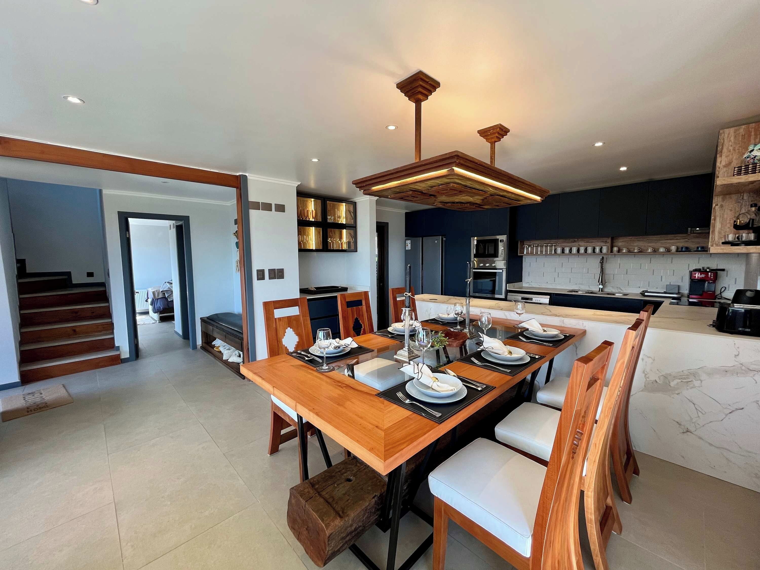 A modern kitchen with a dining area, wooden furniture, and built-in appliances.
