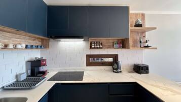 A modern kitchen with dark cabinetry, a coffee machine, a kettle, and a toaster.