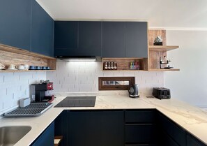 A modern kitchen with dark cabinetry, a coffee machine, a kettle, and a toaster.