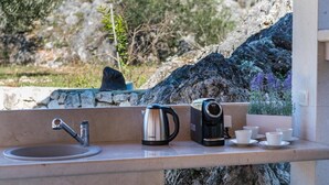 A kitchen area with a sink, kettle, and coffee maker, along with cups and saucers. - Villa Pizzelli (Dubrovnik)