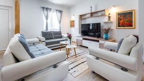 A modern living room with a sofa set, a television, and a small coffee table. - Villa Pizzelli (Dubrovnik)