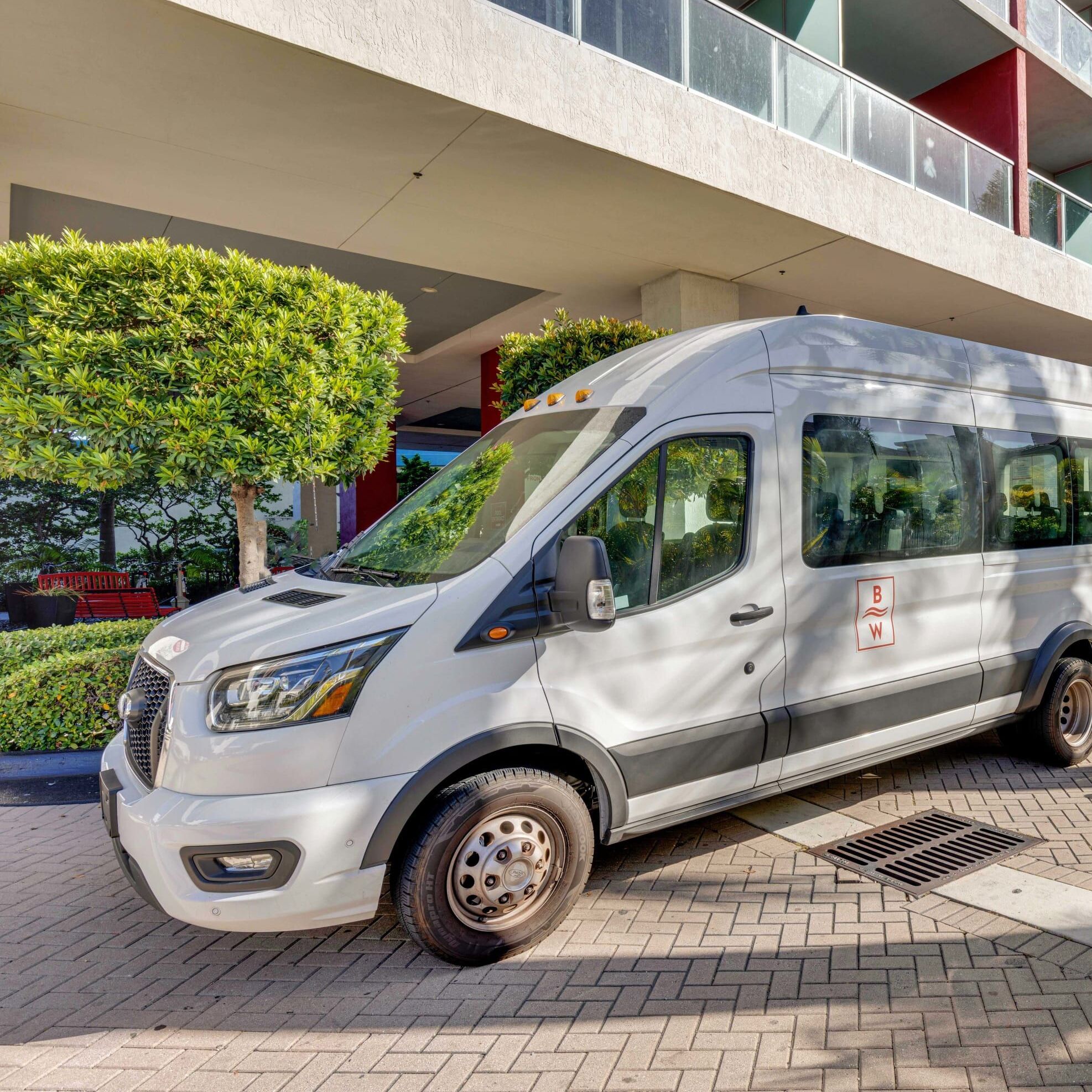 A white van parked in front of a building with a red and white facade.