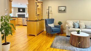 Una sala de estar moderna con un sillón azul, un sofá blanco, un aparador de madera y una planta en maceta.