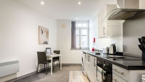 A compact kitchen with a dining area, a window, and a radiator.