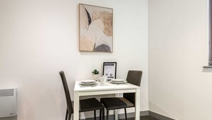 A dining area with a white table, two chairs, and a framed certificate on the wall.