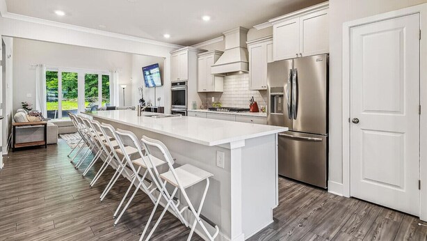 A modern kitchen with a large island, stainless steel appliances, and a view of the outdoors.