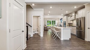 A modern kitchen with a central island, stainless steel appliances, and a view to the outdoors.