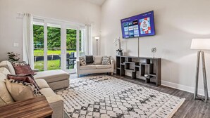 A modern living room with a large TV mounted on the wall, a sofa, a coffee table, and a patterned rug.