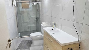 Une salle de bain moderne avec une douche à parois de verre, un lavabo blanc et des toilettes.