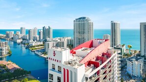 A high-rise hotel with a red and white facade, overlooking a marina and the ocean. - Upper Studio Balcony Pool Gym Near Beach (Hallandale Beach)