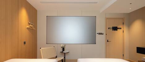 A hotel room with two beds, a flat-screen TV, a small table with a vase, and a chair.