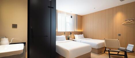Habitación de hotel con dos camas, un escritorio, una silla, un lavamanos y un espejo.