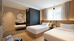 A modern hotel room with two beds, a bedside table, a built-in desk, a large mirror, and a window with curtains. - Captain 5 Youth Hotel Xinzhuang Branch (Shanghai)