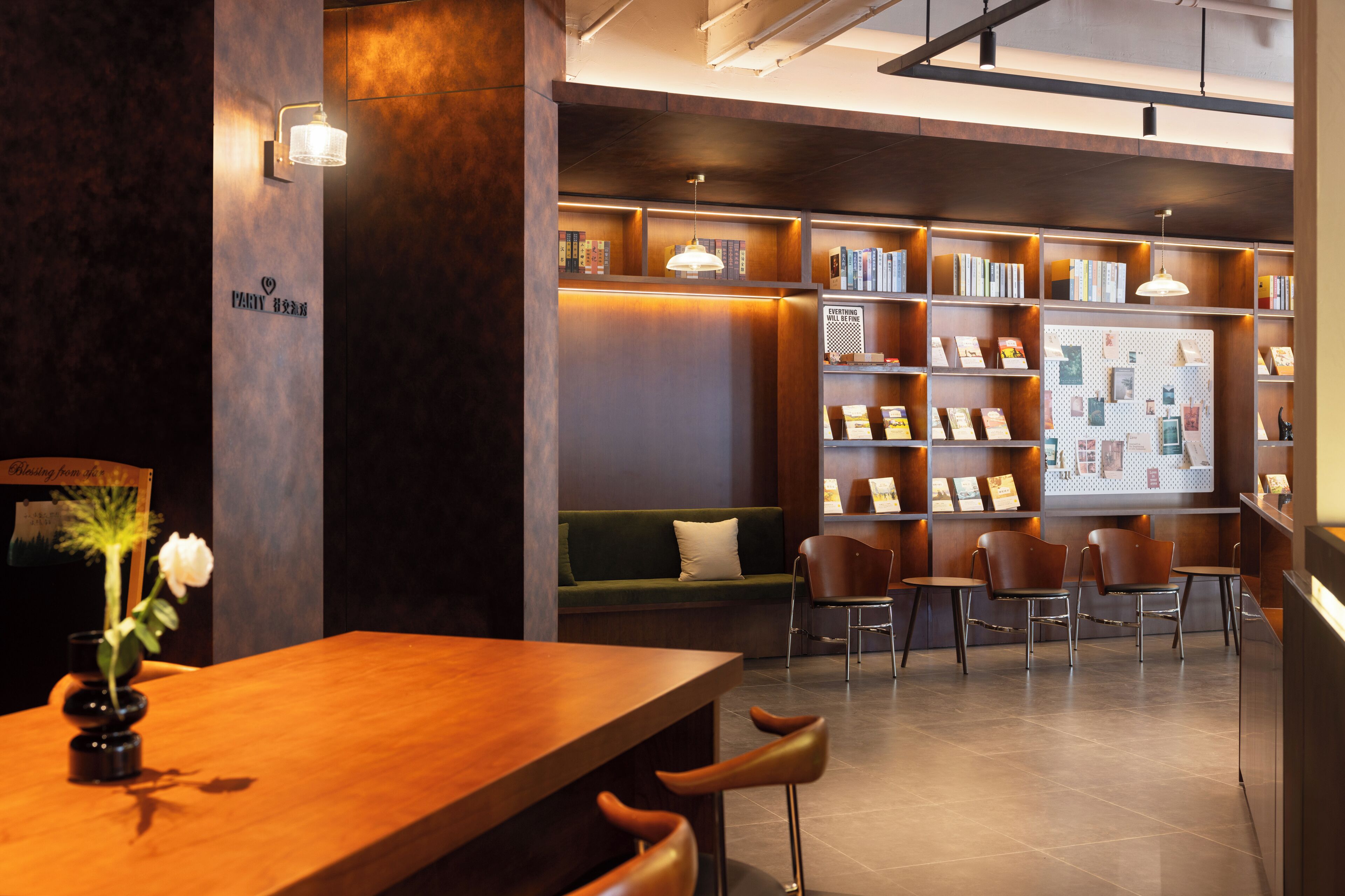 A modern library with bookshelves, a wooden table, and comfortable seating.