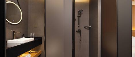 A modern bathroom with a large mirror, a sink, and a shower.
