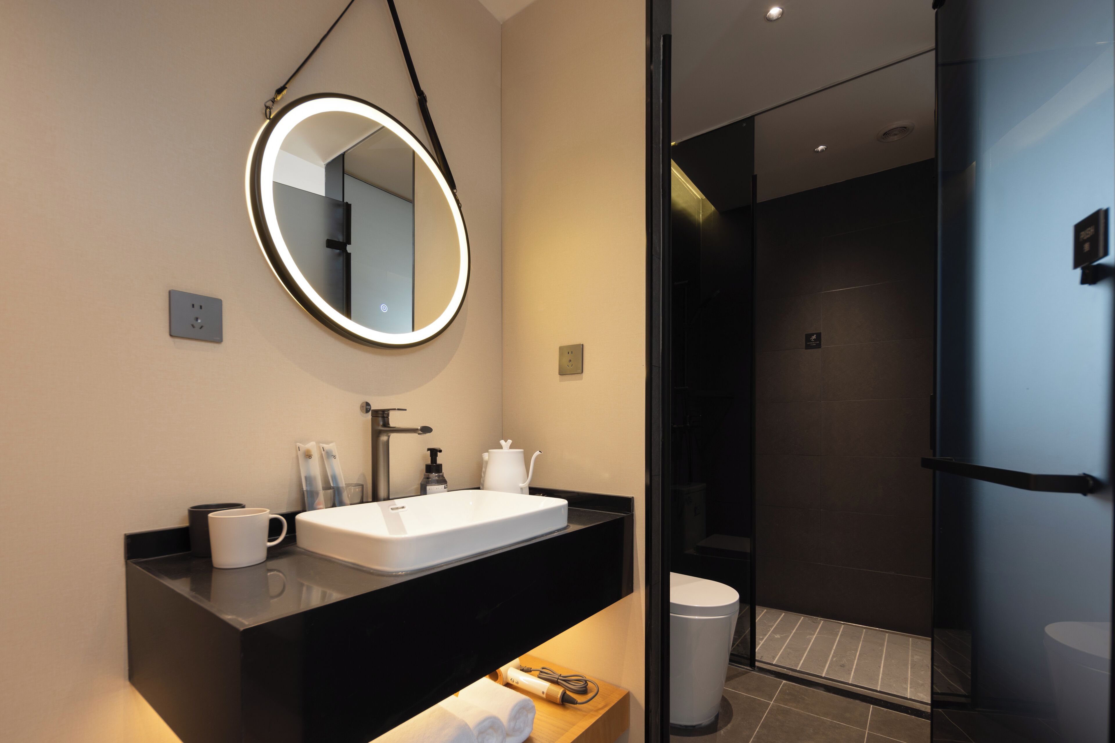 A modern bathroom with a large mirror, sink, and a shower area.