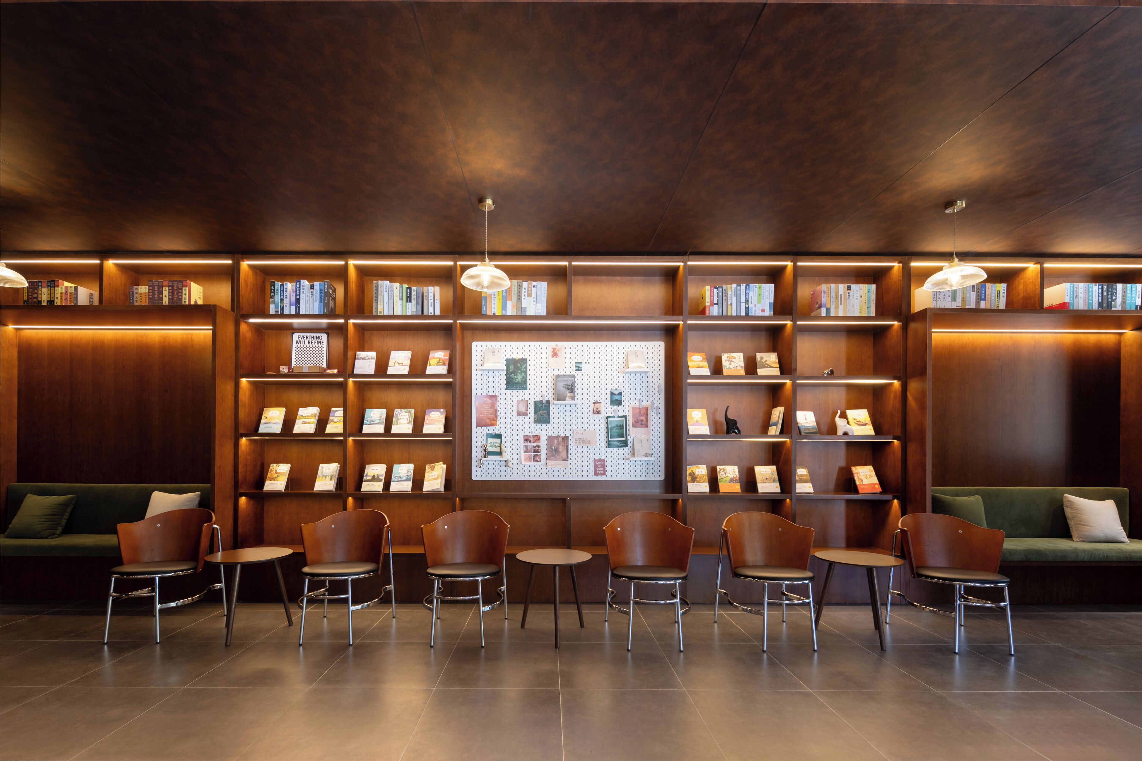 Una biblioteca con estanterías de madera, un tablón de anuncios y zonas de estar.