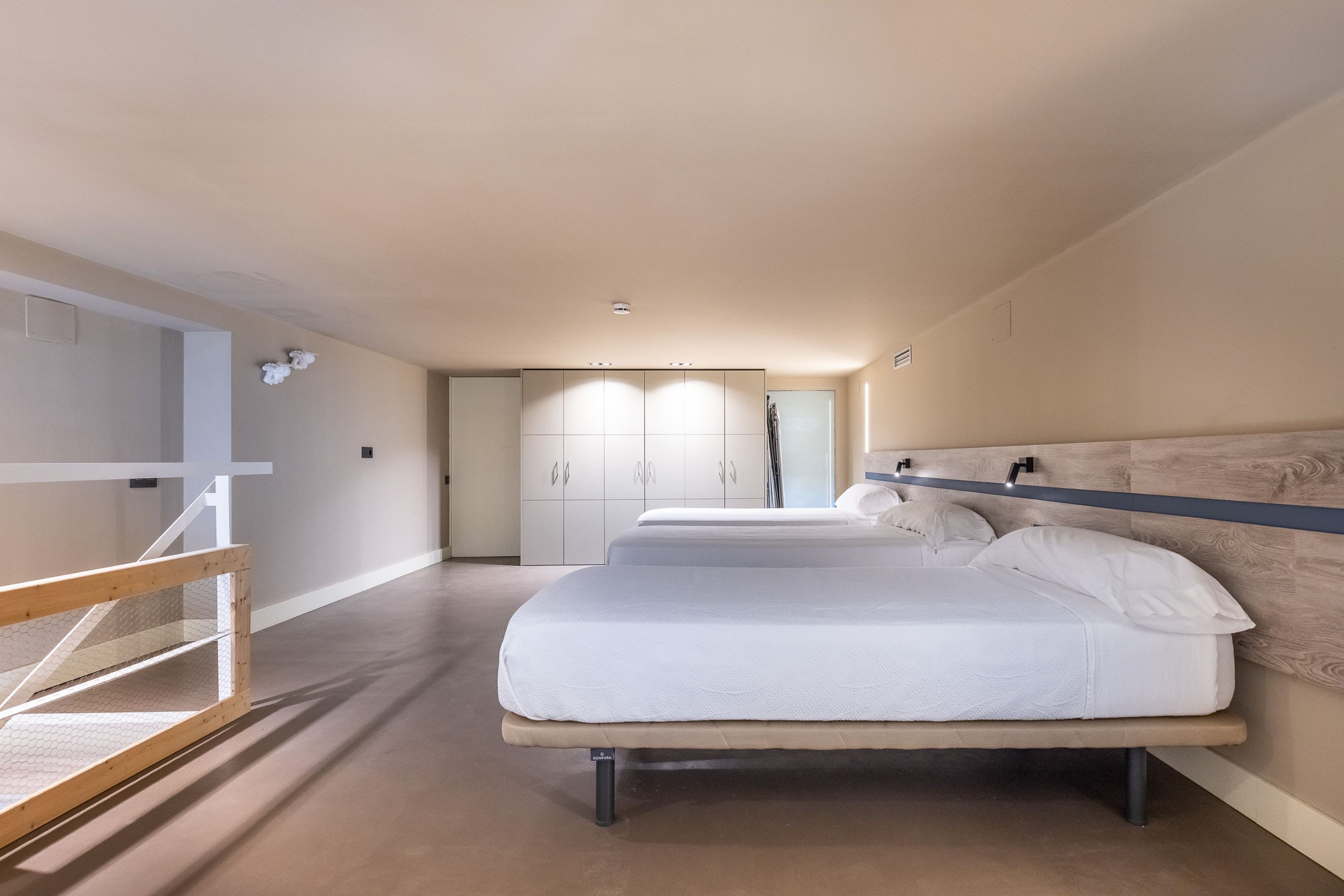 Een moderne hotelkamer met een groot bed, een houten hoofdbord en uitzicht op de hal.