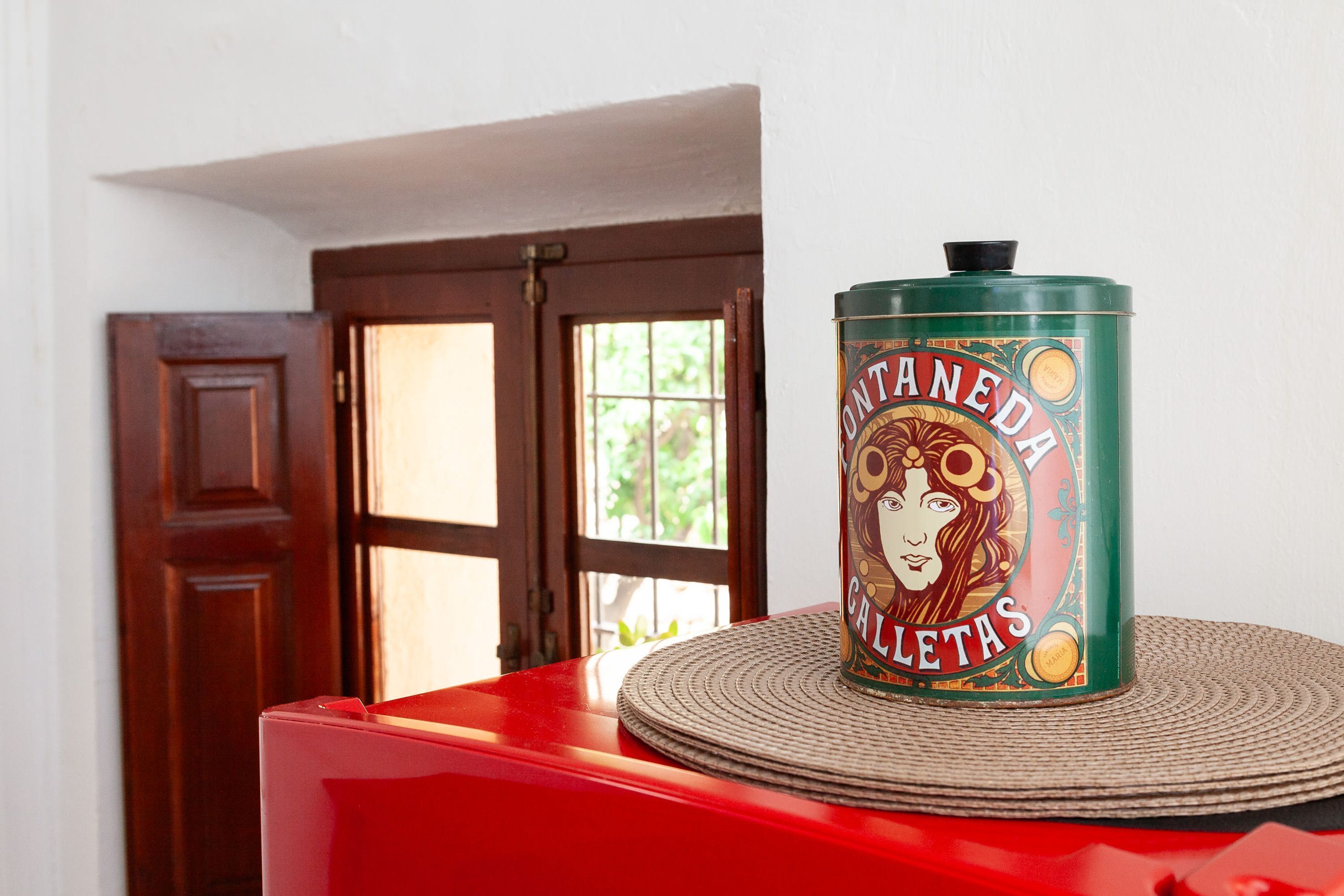 A green tin labeled "Contaneda Callejas" on a red surface with a woven placemat.