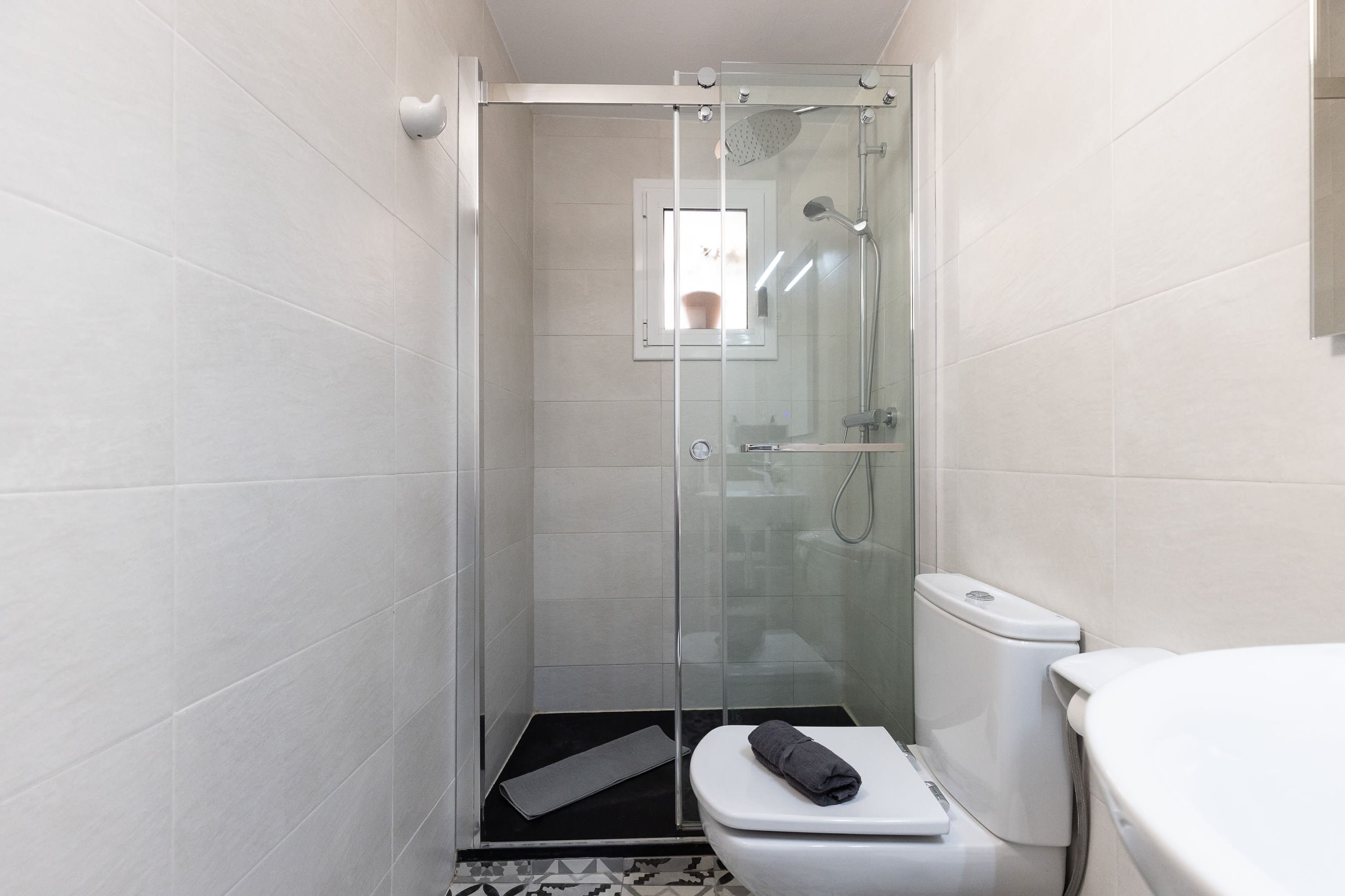 Un baño pequeño con ducha, inodoro y ventana.